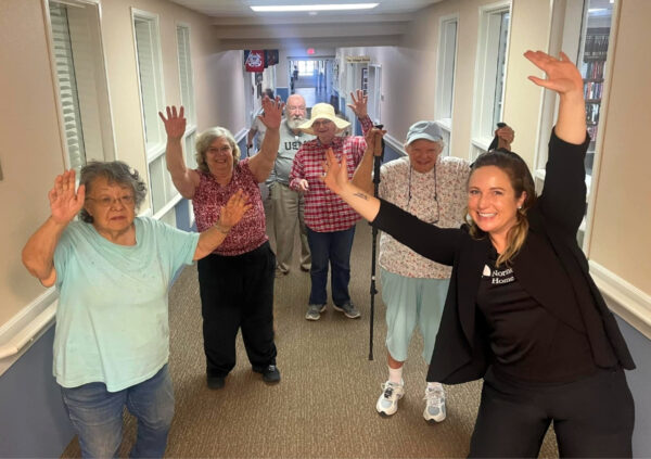 Group of seniors and a therapist stretch together in a hallway at a senior living community in Cottonwood, Arizona.