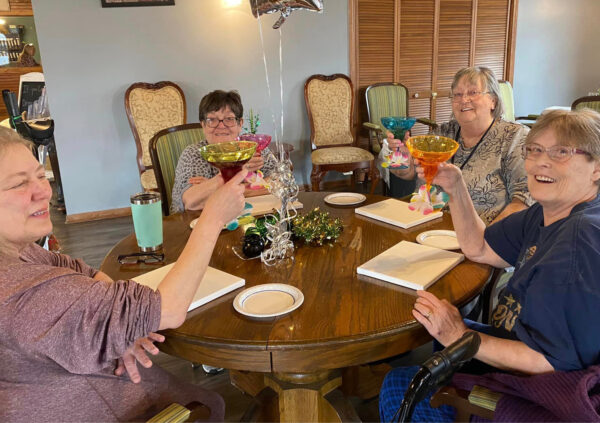 Four senior women enjoy fun drinks together before a painting class at their senior living community in Greenwood, IN.