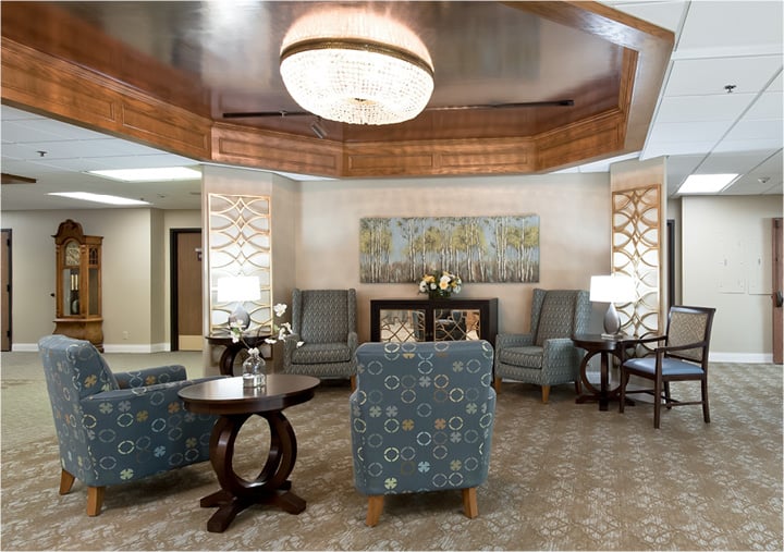 Senior living lounge area with comfortable seating under a beautiful chandelier in Omaha, Nebraska.