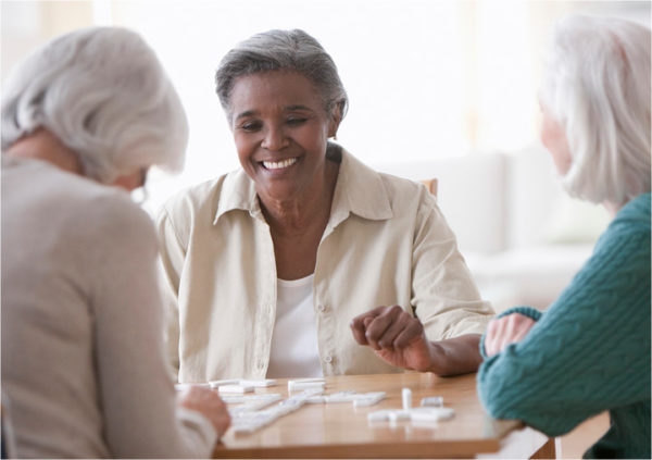 Smiling woman playing dominoes with friends.