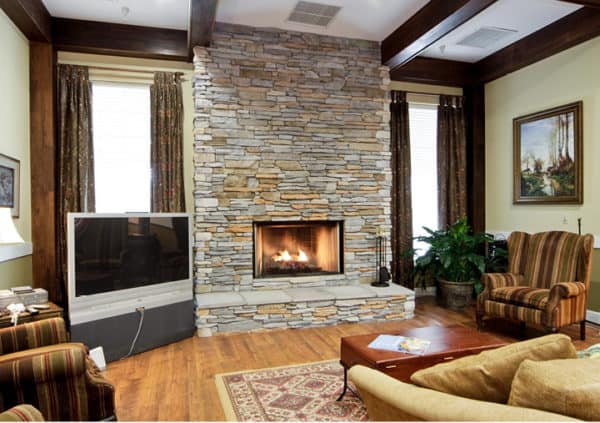 A beautiful, stone fireplace in a comfortable lounge area with couches and a television in Columbus, North Carolina.