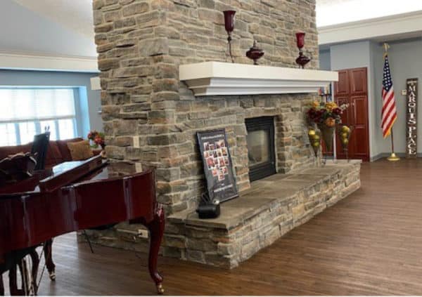 A double-sided, stone fireplace with a grand piano next to it in Elkhorn, Nebraska.