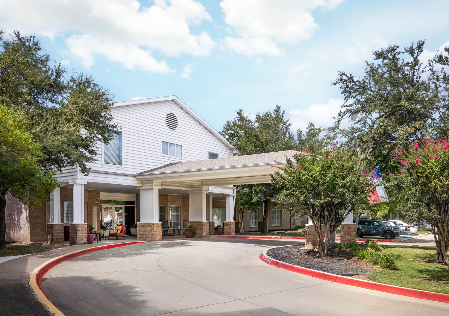Front entrance of a senior living facility in North Richland Hills, The Wellington at North Richland Hills in Texas with covered circular driveway.
