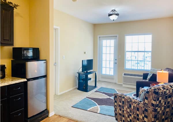 A bright and spacious living room and kitchenette in a model apartment home in North Richland Hills, Texas.