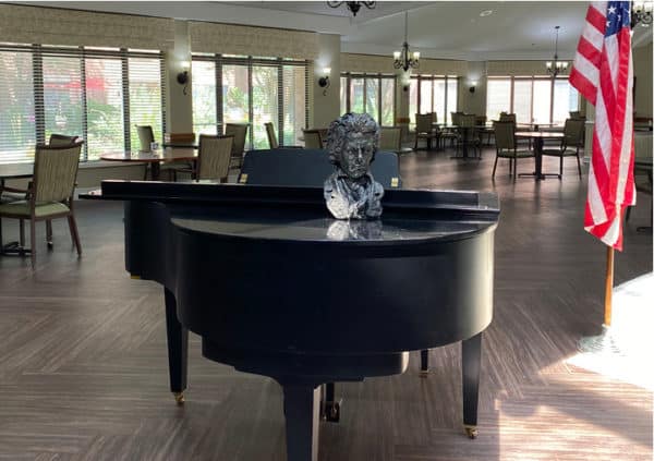 A grand piano and a flag in a senior living great room in Raleigh, North Carolina.