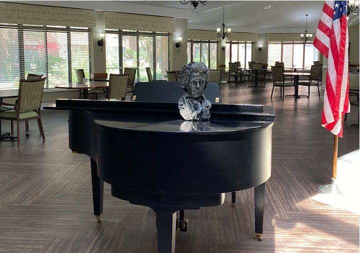 A grand piano and a flag in a senior living great room in Raleigh, North Carolina.