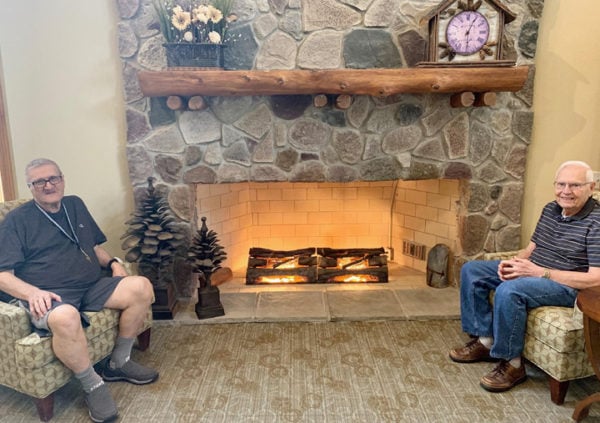 Senior men smiling and chatting in front of a fireplace in Maple Grove, Minnesota.