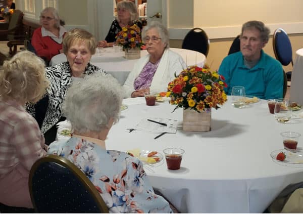 A group of seniors around a dining table with flower centerpiece in Anderson, South Carolina.