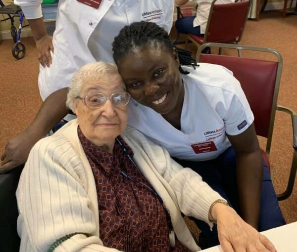 a woman caregiver smiles and hugs a senior woman