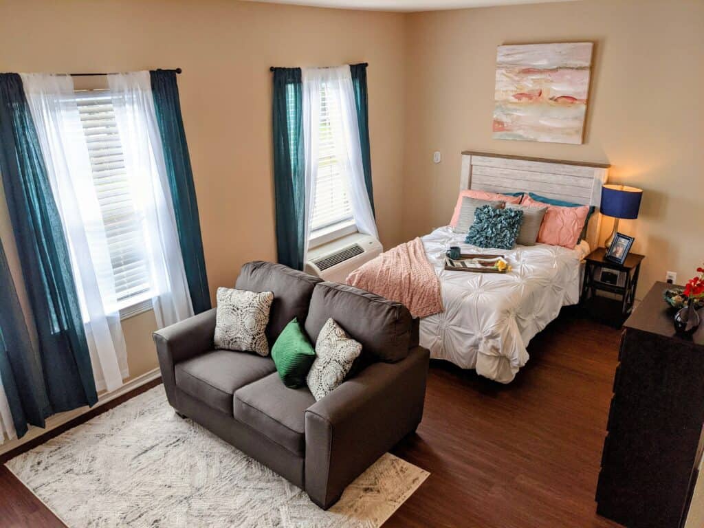 Studio apartment bedroom with bed and couch at a senior living facility in San Antonio, Texas.