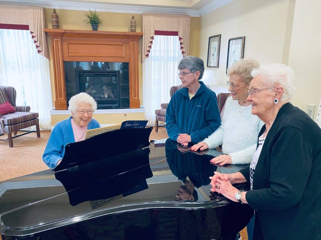 Senior women gather around the piano at a senior living community in Dayton, Ohio.