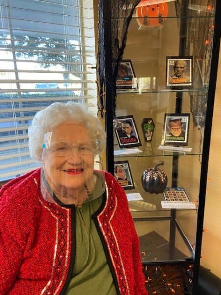 Senior woman smiles near a display of pictures at a senior living facility in Fort Worth, Texas.