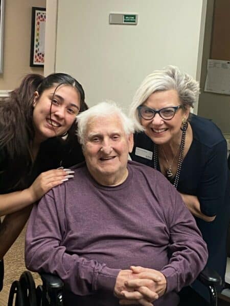 Two employees and a senior man smile at a senior living community in Cottonwood, Arizona.