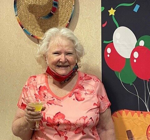 Senior woman enjoys a drink during a party at a senior living facility in Fort Worth, Texas.