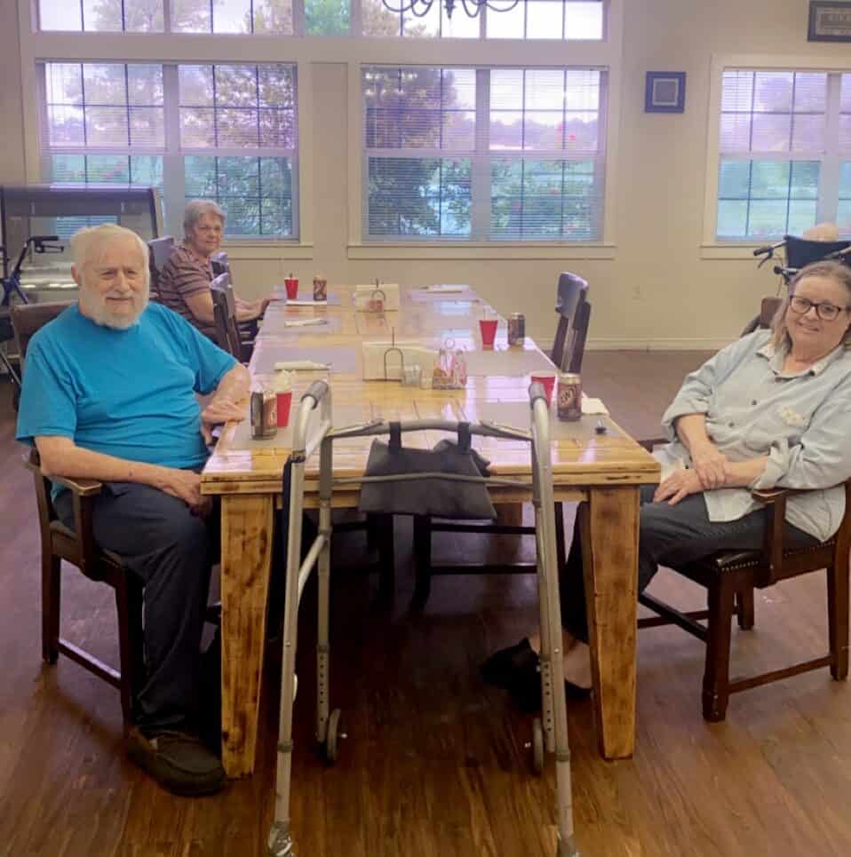 Two seniors smiling at dinner at Good Tree senior living in Stephenville, Texas.