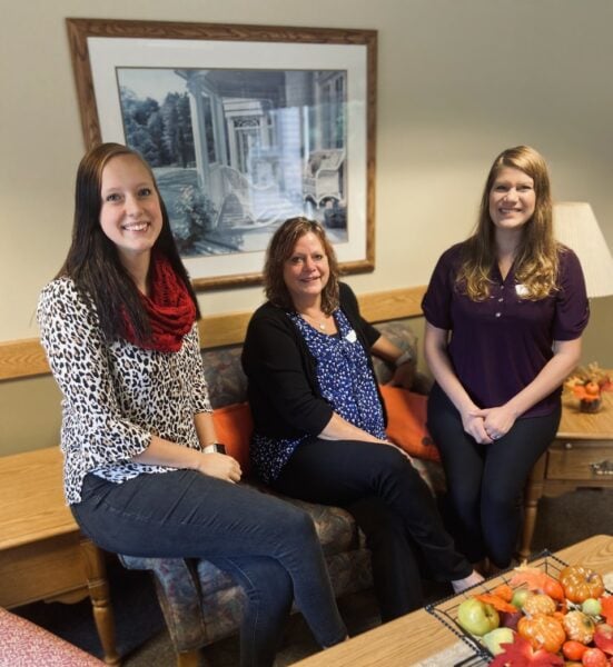 Three employees smile together while working at a senior living community in West Bend, Wisconsin.