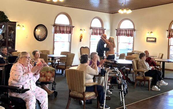 group of eight seniors clap while listening to a performer play music