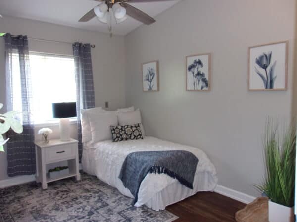 Apartment bedroom area with twin bed near window at a senior living facility in Pensacola, Florida.