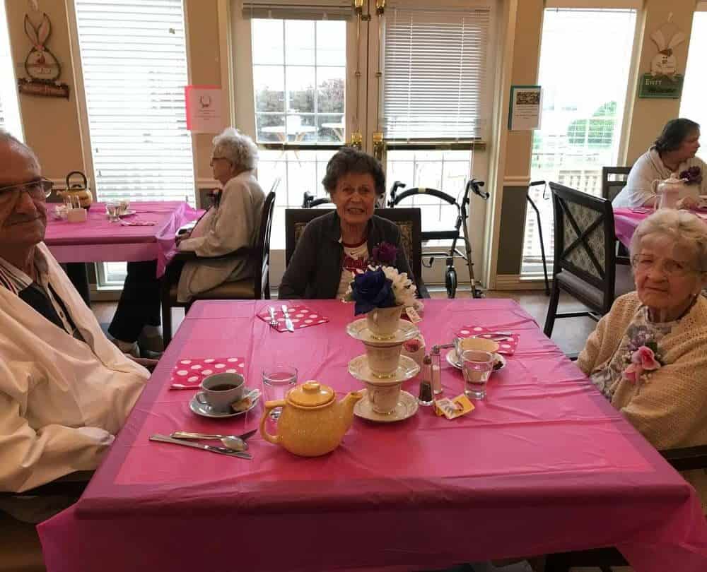 Senior man and two senior women smile at dinner at a senior living community in Chardon, Ohio.