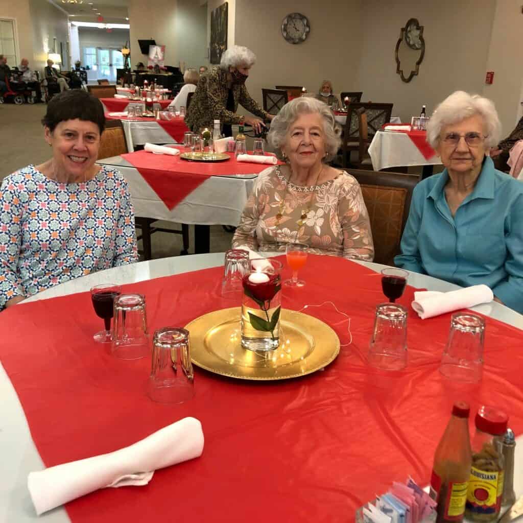 Three senior women smile while at dinner at senior living community in Ridgeland, Mississippi.