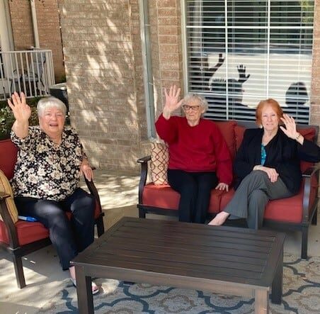 Senior women smile and wave at the camera at senior living community in North Richland Hills, Texas.