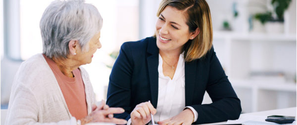 A financial planner smiling and helping a senior woman.
