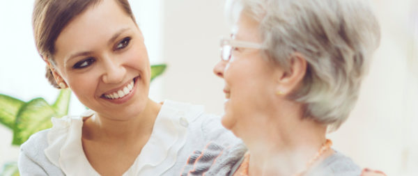 A smiling caregiver with her arm around a resident.