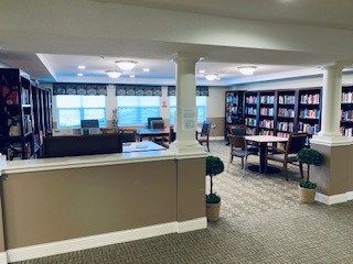 Library inside The Harrison, a senior community in Indianapolis, Indiana with rows of books and ample seating.