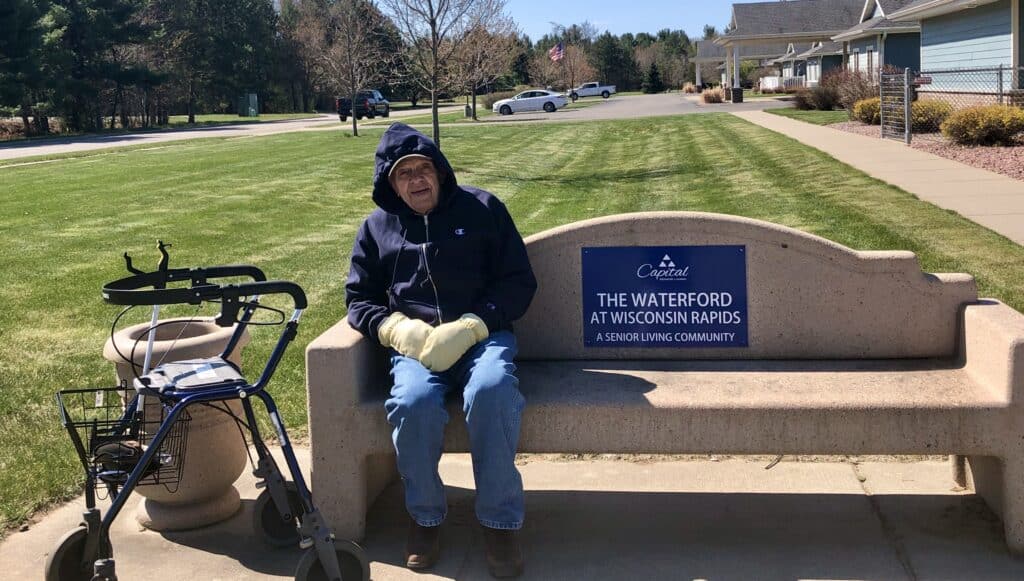 Senior man sits on a bench outside a senior living community in Wisconsin Rapids, Wisconsin.