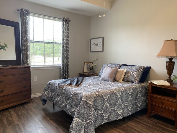 Model bedroom with bed, dress and two nightstands at a senior living community in Lake Granbury, Texas.