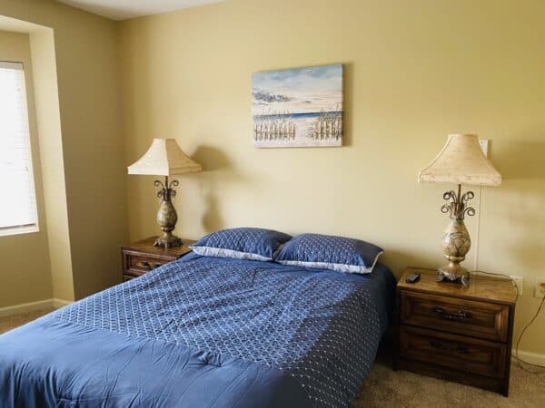 Senior apartment bedroom with queen bed and two side tables with lamps in Cincinnati, Ohio.