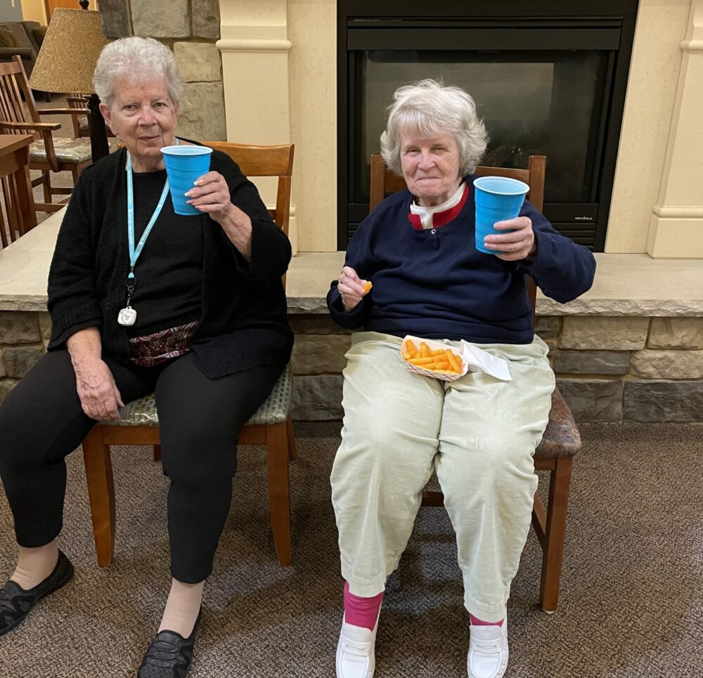 two senior women smile with their drinks during happy hour