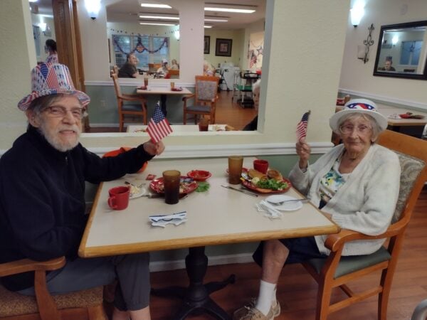 Senior woman and senior man eat together on the Fourth of July at a senior living community in Jeffersonville, Indiana.