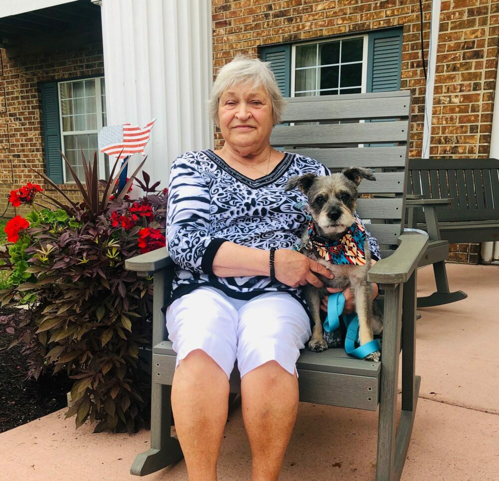 Senior woman sits with her small pet dog at a senior living community in Fort Wayne, Indiana.