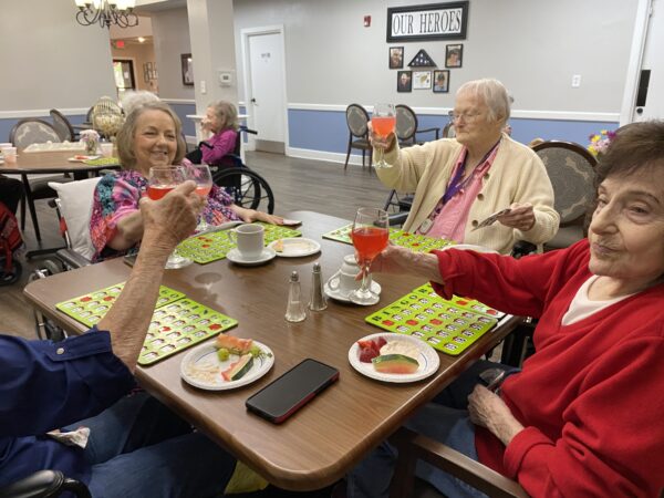 Four seniors play Bingo and eat food together at a senior living community in Conroe, Texas.