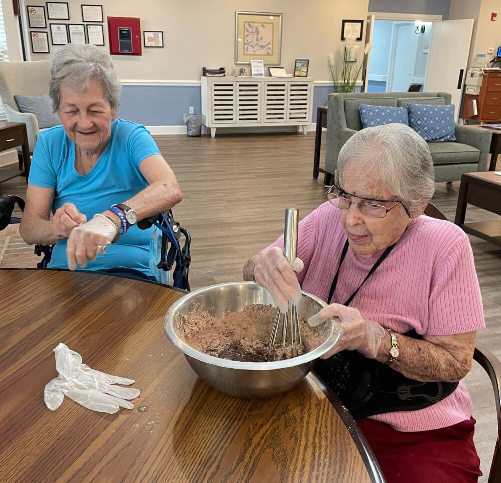 Two senior women make a chocolate treat together at a senior living community in Conroe, Texas.