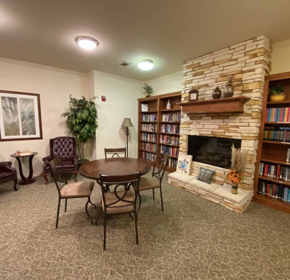 Library with seating and fireplace at a senior living community in Granbury, Texas.