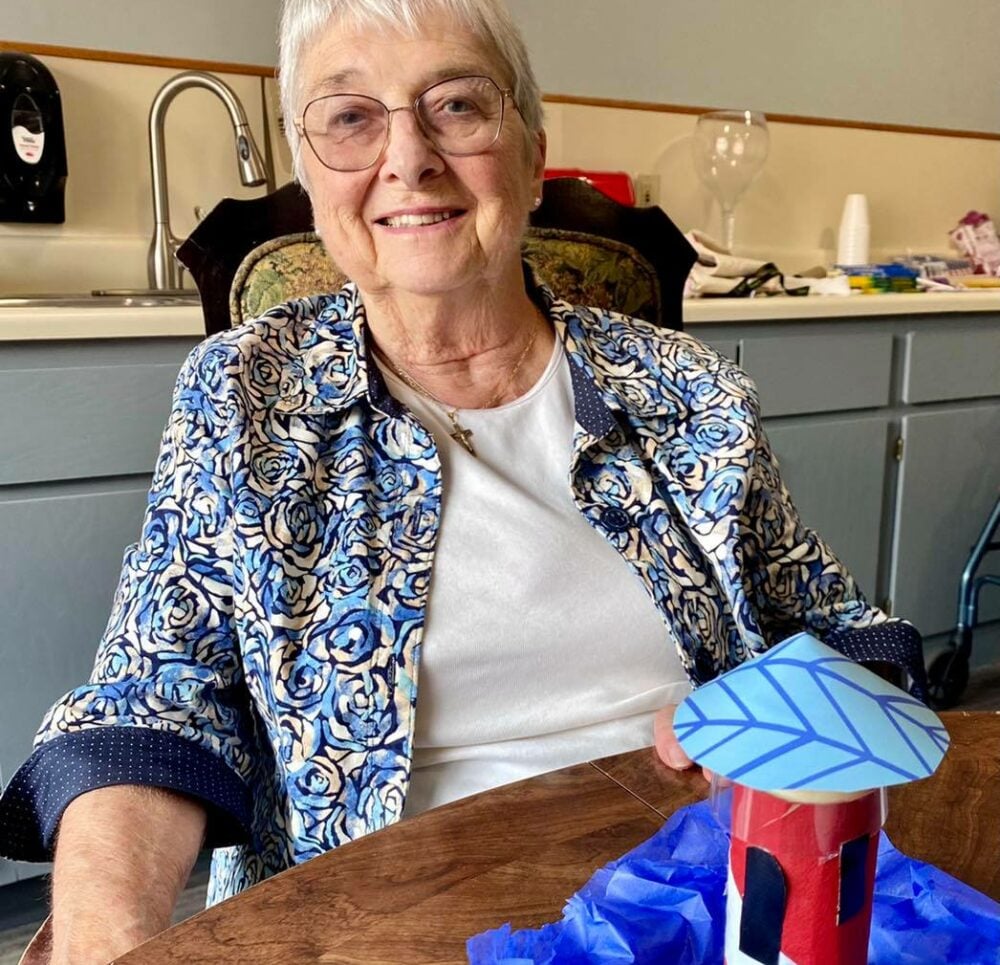 Senior woman smiles with her homemade craft project at a senior living community in East Lansing, Michigan.