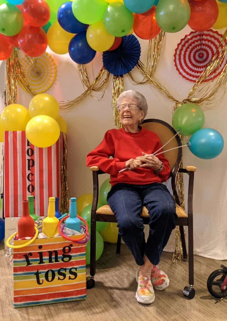 Senior woman smiling during a carnival party at a senior living facility in San Antonio, Texas.