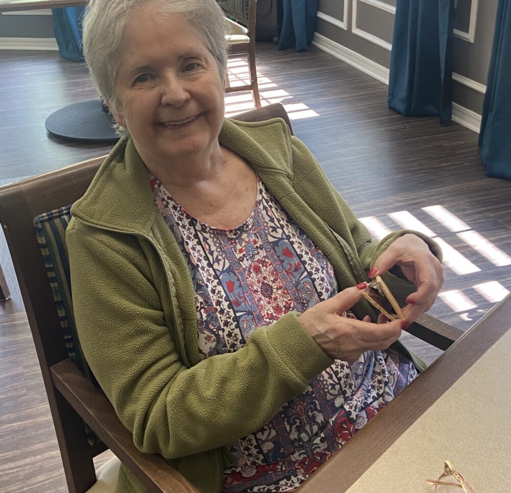 Senior woman smiles while holding a smore at a senior living community in College Station, Texas.