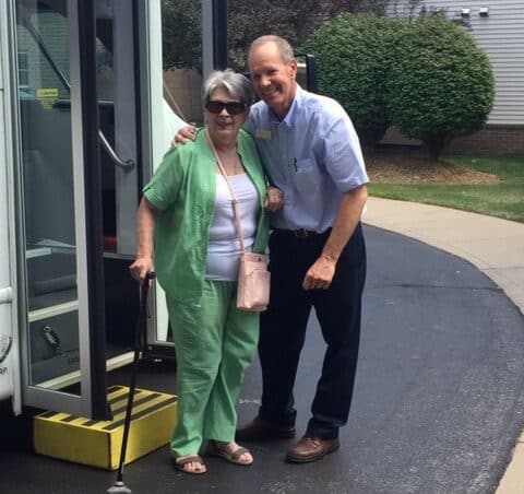 Senior woman smiles with a bus driver at the Waterford at Ironbridge in Springfield, Missouri.