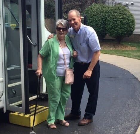 Senior woman smiles with a bus driver at the Waterford at Ironbridge in Springfield, Missouri.