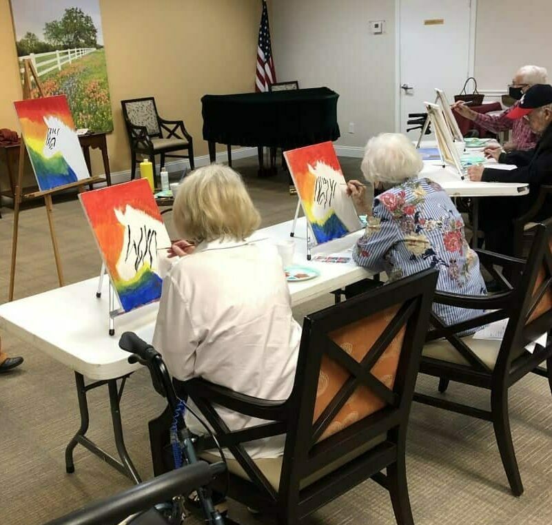 Seniors painting a canvas during a class at a senior living community located in Ridgeland, Mississippi.