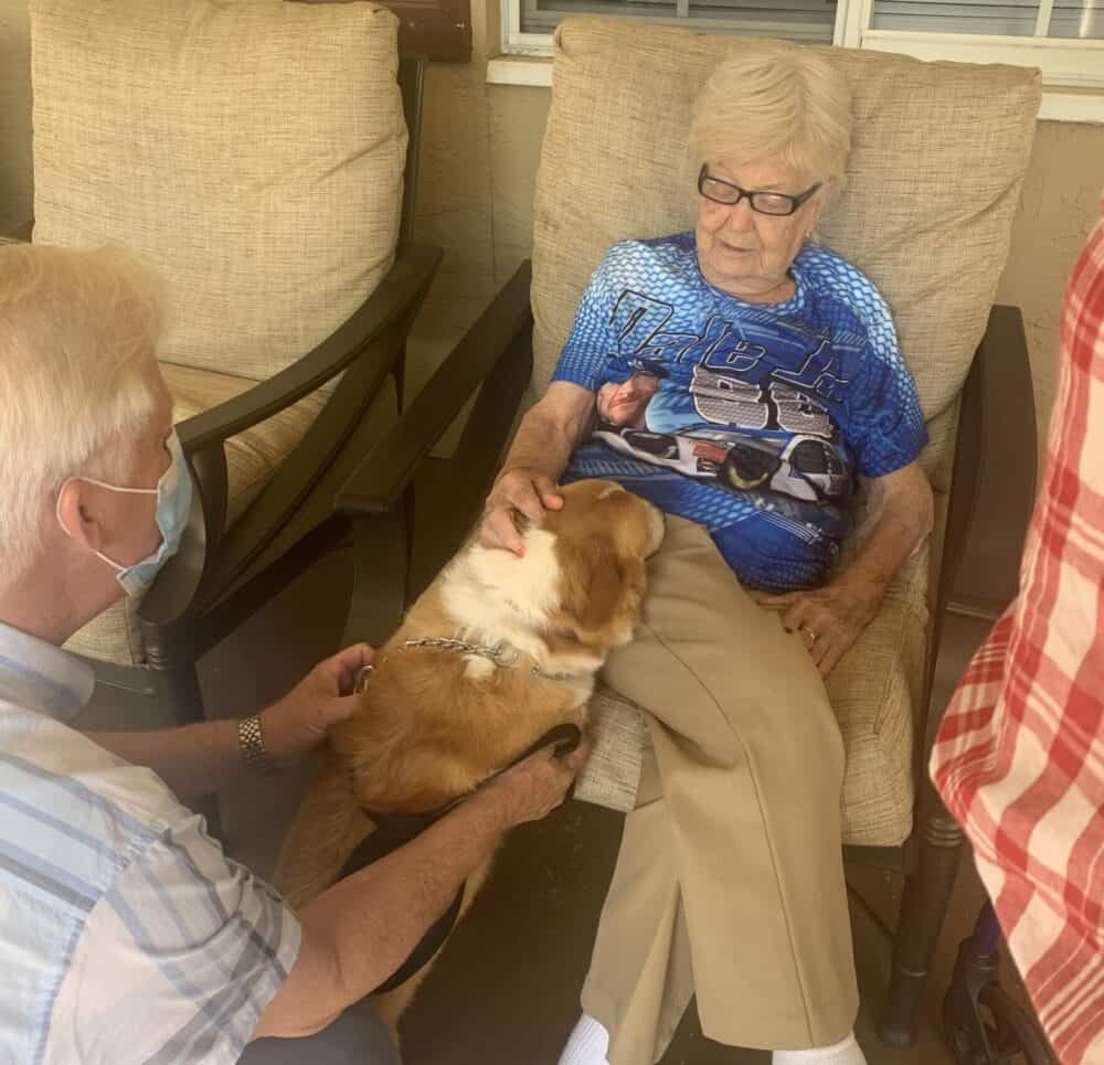 Senior woman pets a therapy dog at a memory care community in Pensacola, Florida.