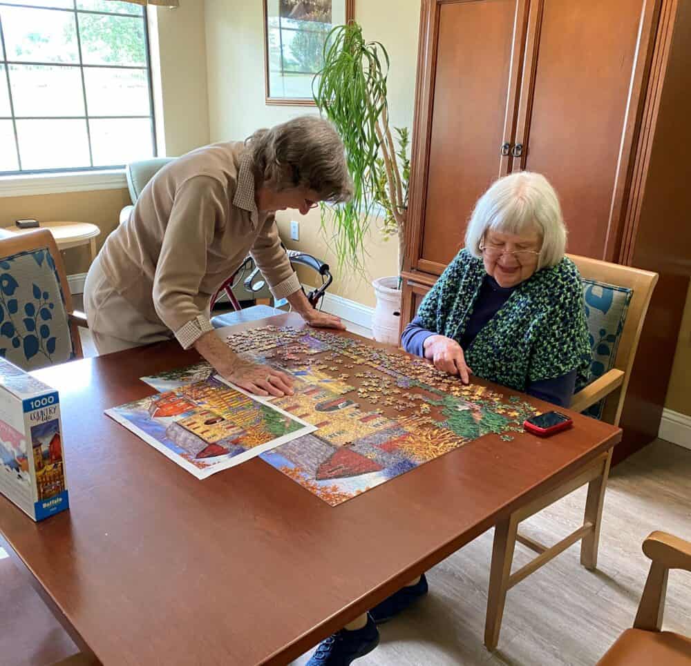 Two senior women solving a puzzle at a senior living facility in Granbury, Texas.