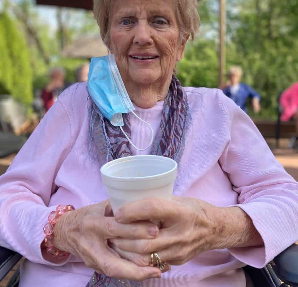 Senior woman enjoying a drink outside at a senior living facility in Greenwood, Indiana.