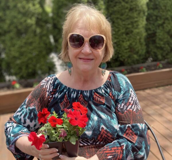 Senior woman smiles with her red flowers at a senior living facility in Greenwood, Indiana.