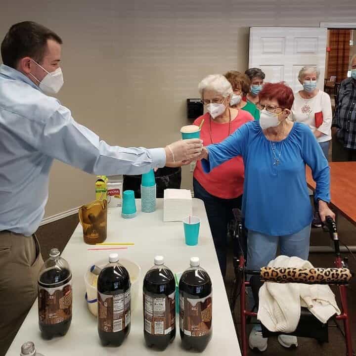Employee serves root beer floats to seniors at a senior living community in San Antonio, Texas.