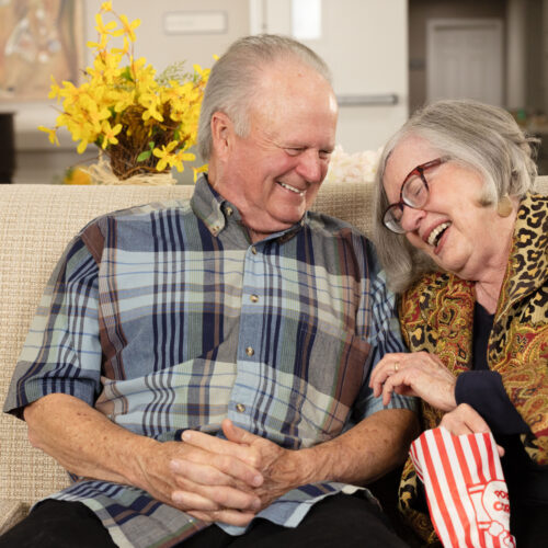 Senior couple laughing and eating popcorn