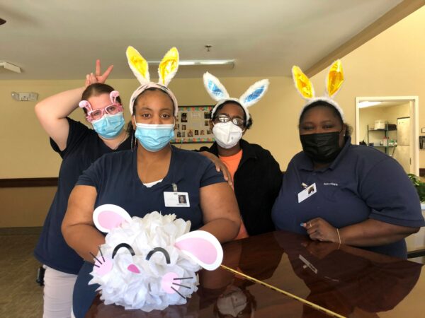 Four women employees pose together during Easter at a senior living community in Anderson, South Carolina.